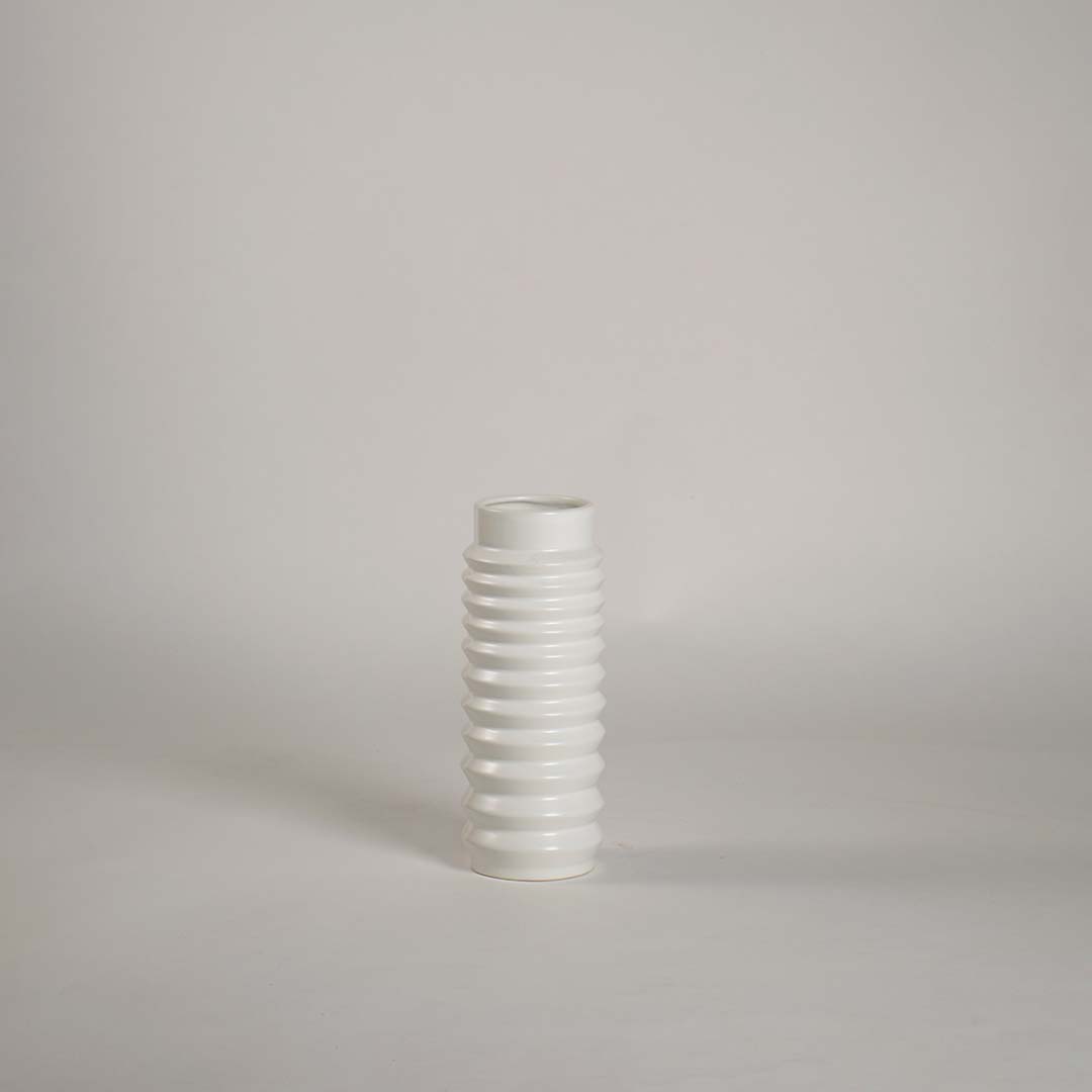 Glossy ribbed white ceramic vase displayed on plain white backdrop emphasizing texture and minimal design.