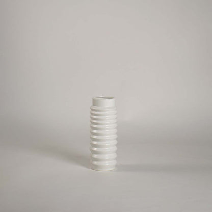 Glossy ribbed white ceramic vase displayed on plain white backdrop emphasizing texture and minimal design.