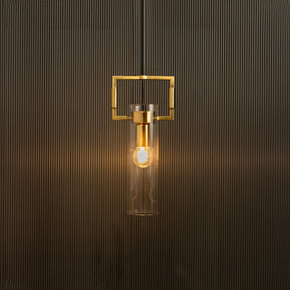 Modern pendant light with clear glass cylinder and gold frame glowing warmly against a textured black background.