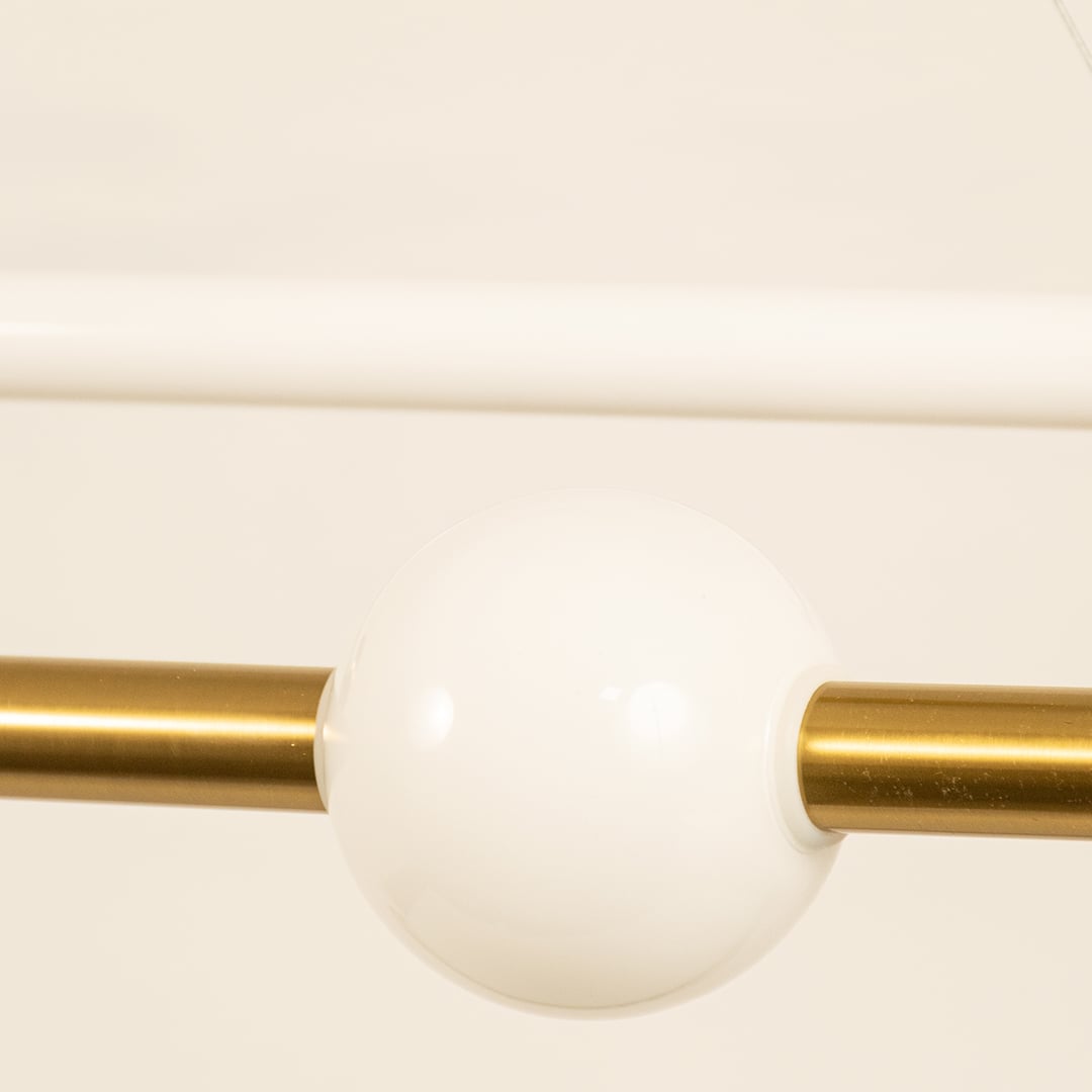 Gold metal linear pendant light closeup featuring frosted globe detail and premium modern lighting design.
