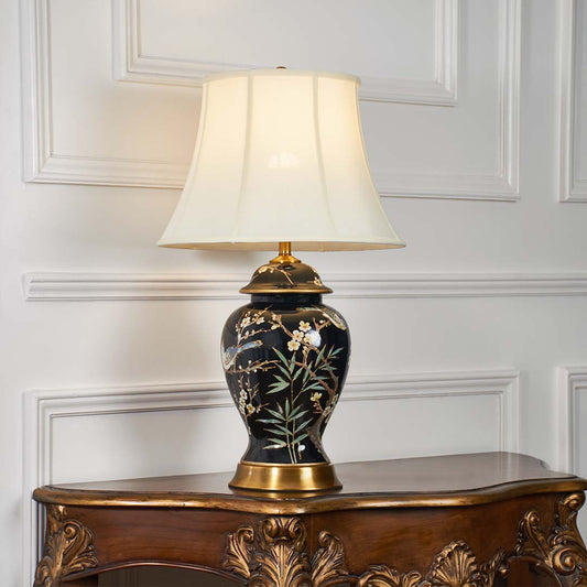 Black floral ceramic table lamp with fabric shade displayed on a carved wooden console table creating elegant ambient lighting.