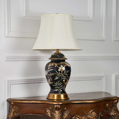Black ceramic floral table lamp with gold accents displayed with light off on a white background showcasing its glossy finish and ornate details.