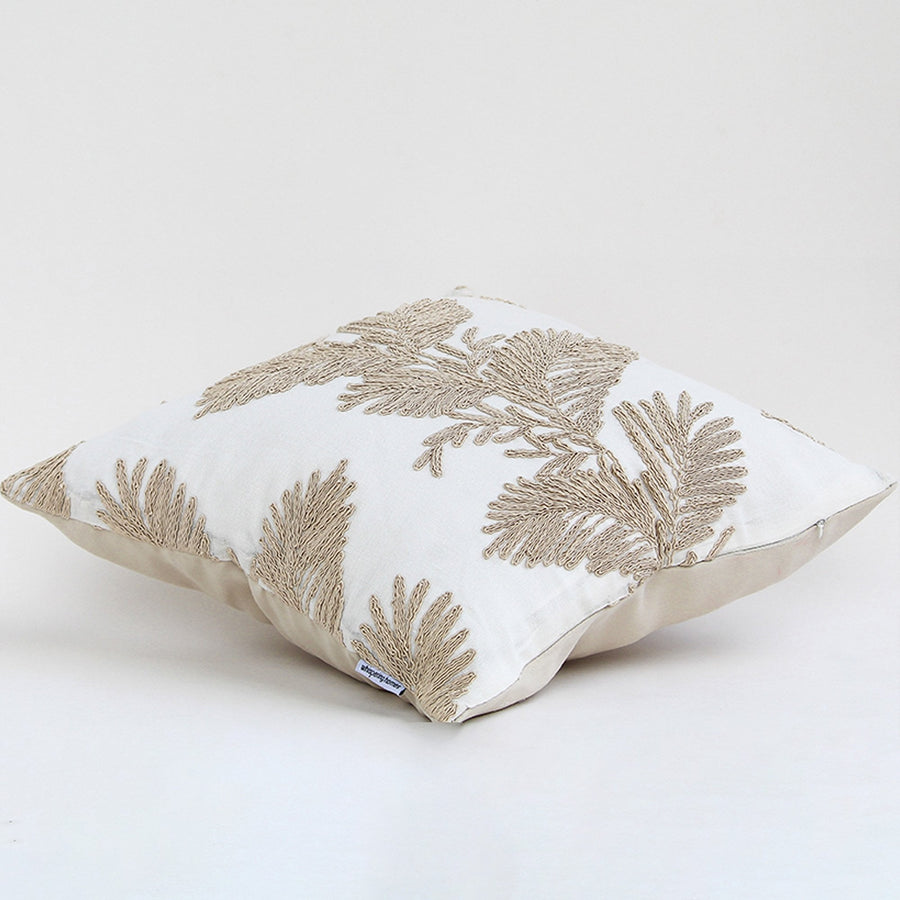 Soft cotton cushion cover with beige floral embroidery shown at an angle providing an elegant nature inspired décor element with a breathable smooth and skin friendly fabric texture.