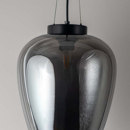 Closeup of smoked glass pendant light with black suspension showing reflective surface and elegant curved shade design.