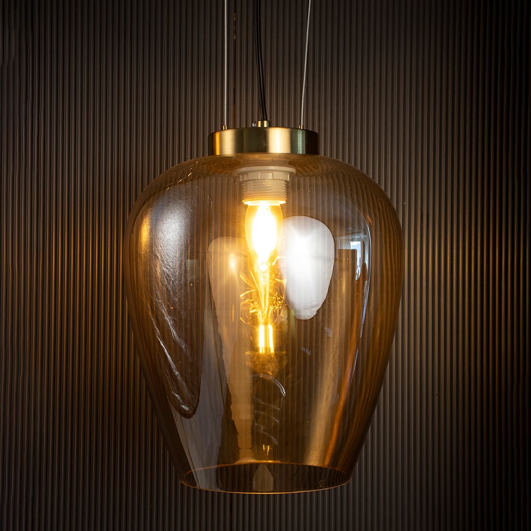 Amber glass pendant light glowing warmly against a dark background highlighting its translucent amber hue.