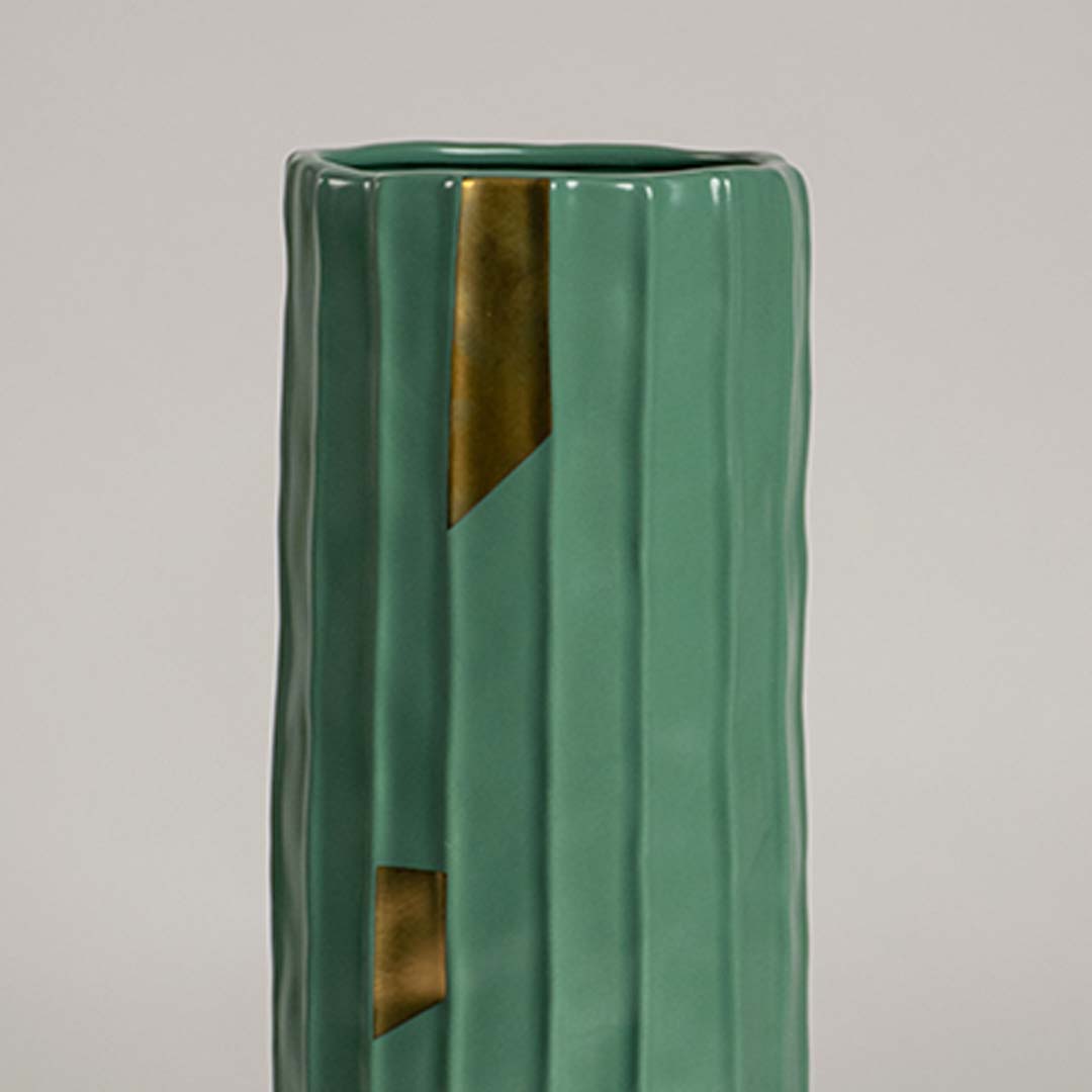 Closeup of green ribbed ceramic vase featuring glossy finish and gold accent details ideal for stylish modern home decor accents.