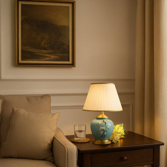 Table lamp with light blue ceramic base and pleated white shade styled for elegant home decor on a warm classic console.