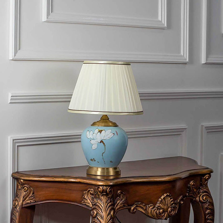 Lotus lamp turned off with detailed ceramic base and golden accents on white background.