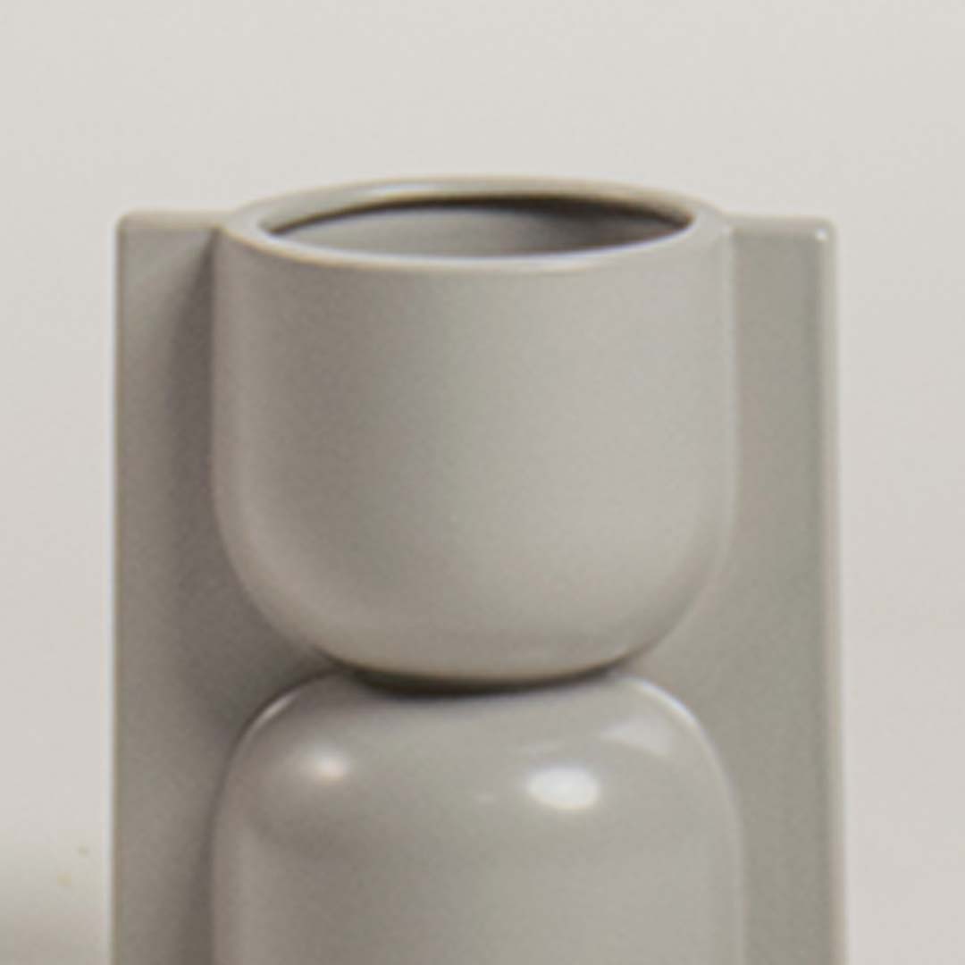 Closeup of light grey geometric ceramic vase showing its smooth glossy finish and sculptural form ideal for modern artistic decor.