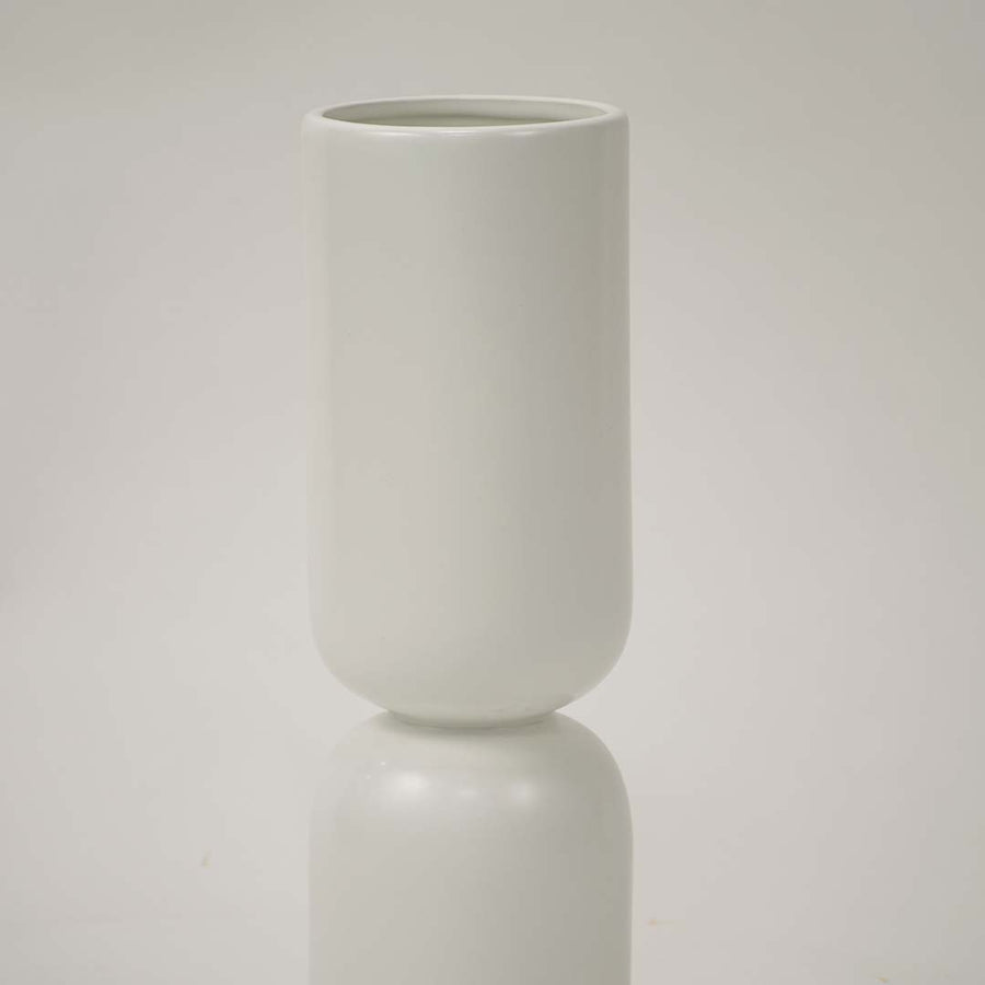 Closeup image of a minimalist matte white ceramic totem vase showing its smooth stacked pill shape and seamless joints.