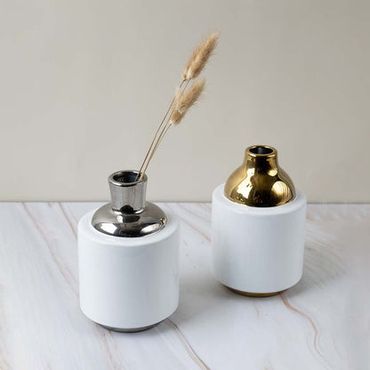 Set of white ceramic vases with gold and chrome metallic tops displayed together highlighting their coordinated modern design and elegant reflective finish.
