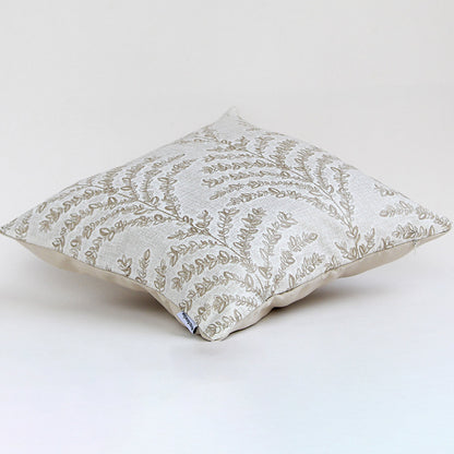 Soft beige cushion with leafy embroidery shown against a white background highlighting its elegant design.