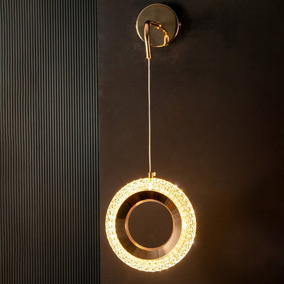 Contemporary gold crystal pendant light turned on glowing beautifully against black background decor.