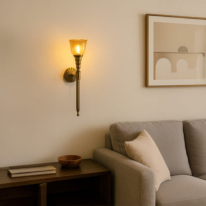 Vintage brass wall sconce with amber glass shade mounted on cream wall creating elegant traditional home lighting decor.