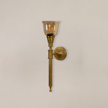 Classic brass wall light fixture with amber tinted glass shade switched off displayed on minimal white backdrop setting.