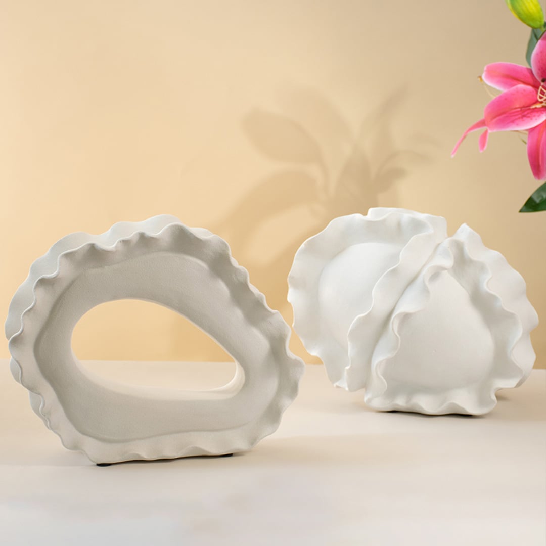Collection of white sculptural ceramic vases with wave-edge design displayed together for an artistic home decor look.