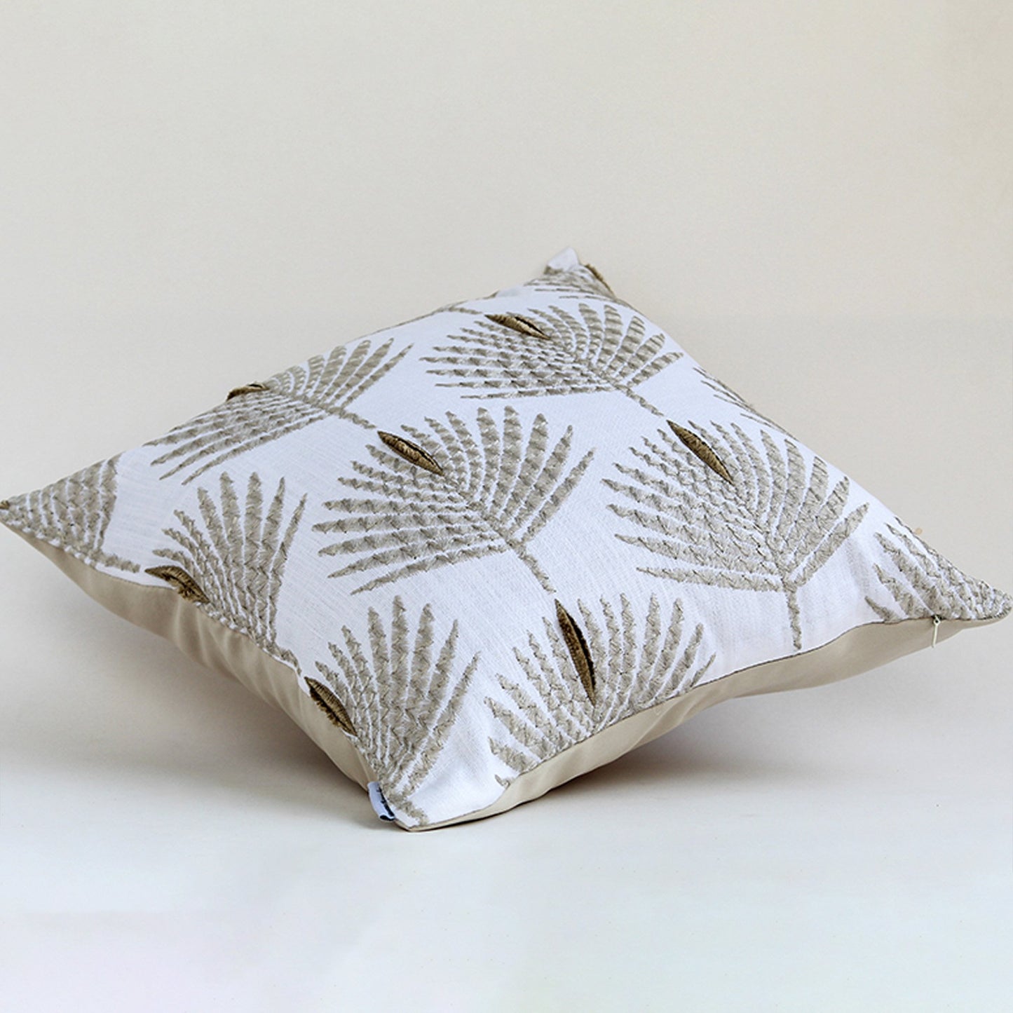 Cream cushion with textured leaf embroidery displayed on a white background highlighting its detailed stitching soft fabric texture and elegant design.