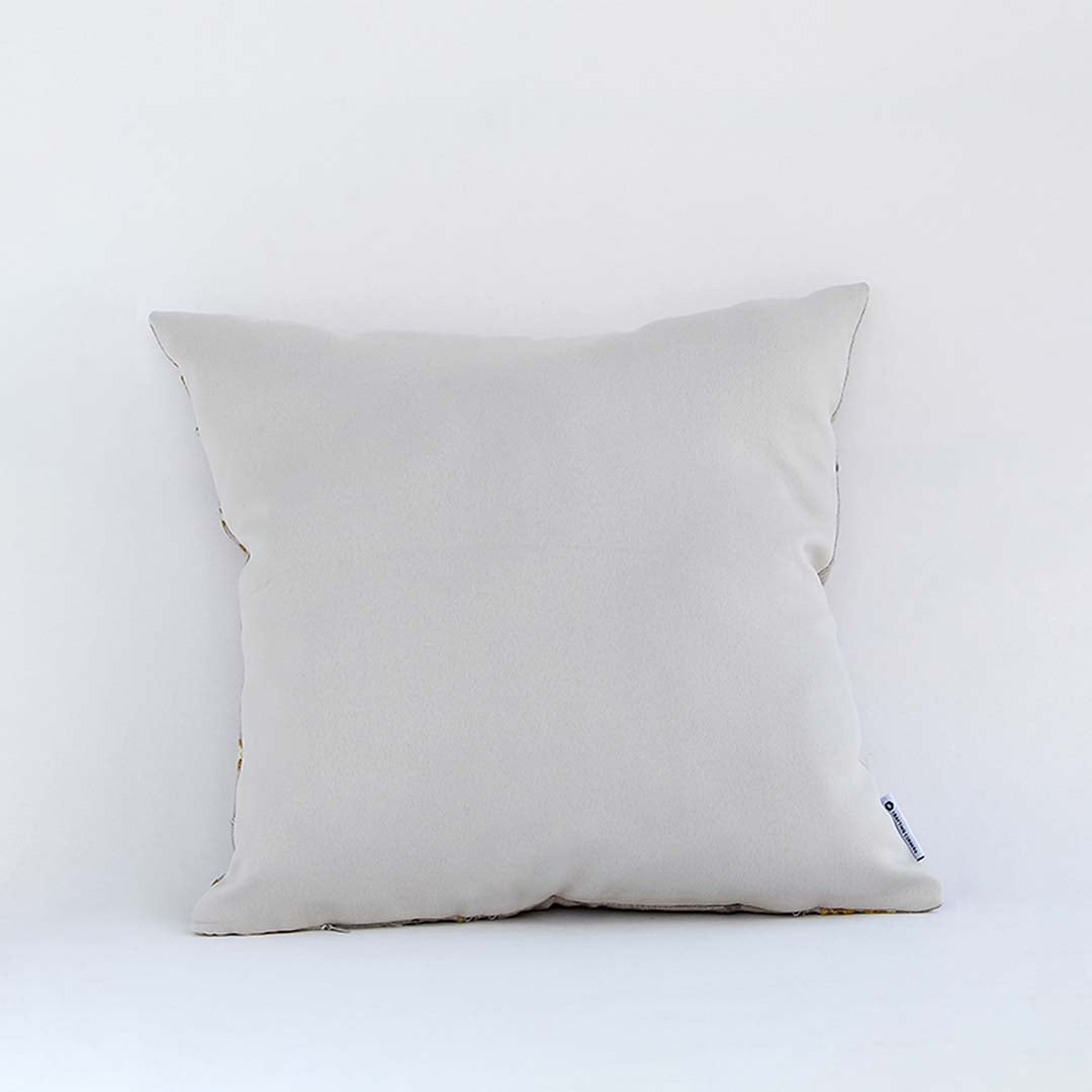 Cream cushion with raised leaf embroidery shown from a soft angled back view highlighting its texture plush form and natural modern decorative appeal.