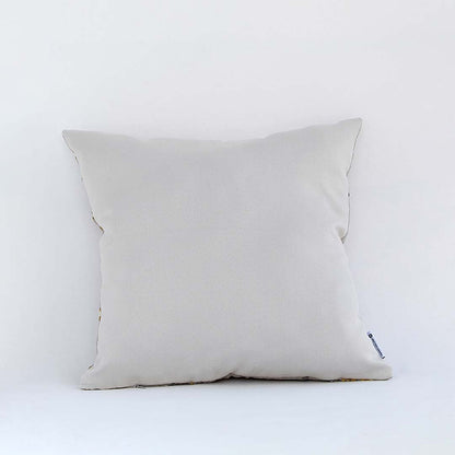Cream cushion with raised leaf embroidery shown from a soft angled back view highlighting its texture plush form and natural modern decorative appeal.