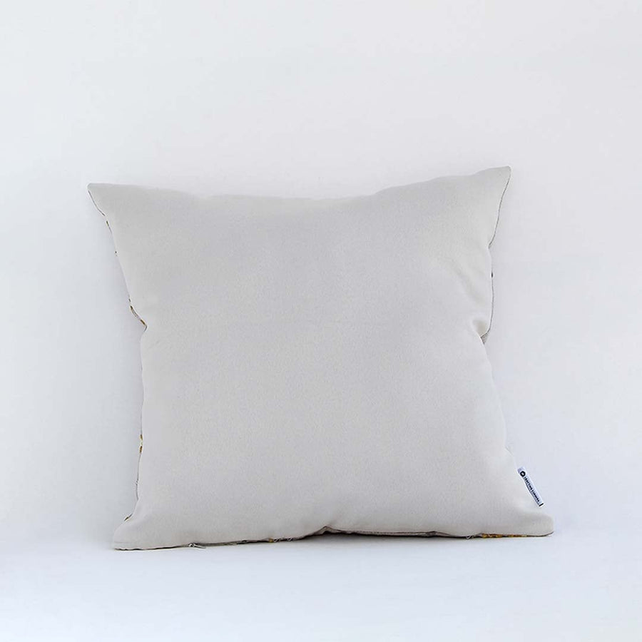 Cream cushion with raised leaf embroidery shown from a soft angled back view highlighting its texture plush form and natural modern decorative appeal.