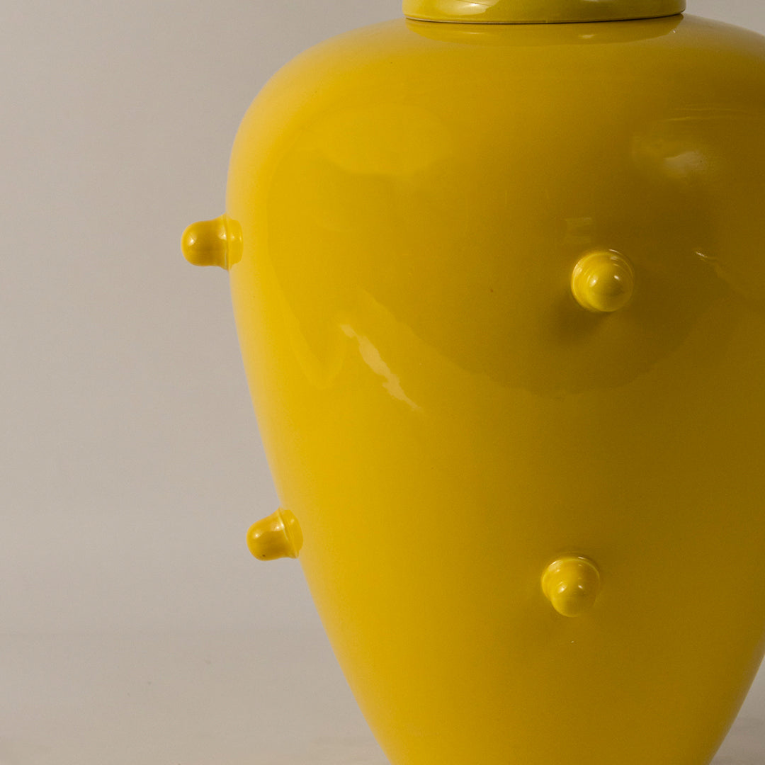 Bright yellow ceramic vase with raised knob texture placed on white surface against neutral background closeup highlighting bold modern home decor styling.
