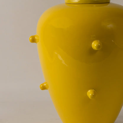 Bright yellow ceramic vase with raised knob texture placed on white surface against neutral background closeup highlighting bold modern home decor styling.