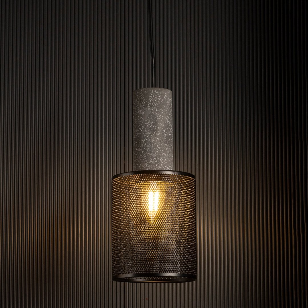 Arlo Mesh pendant light glowing against a dark background highlighting industrial texture and warm filament light.