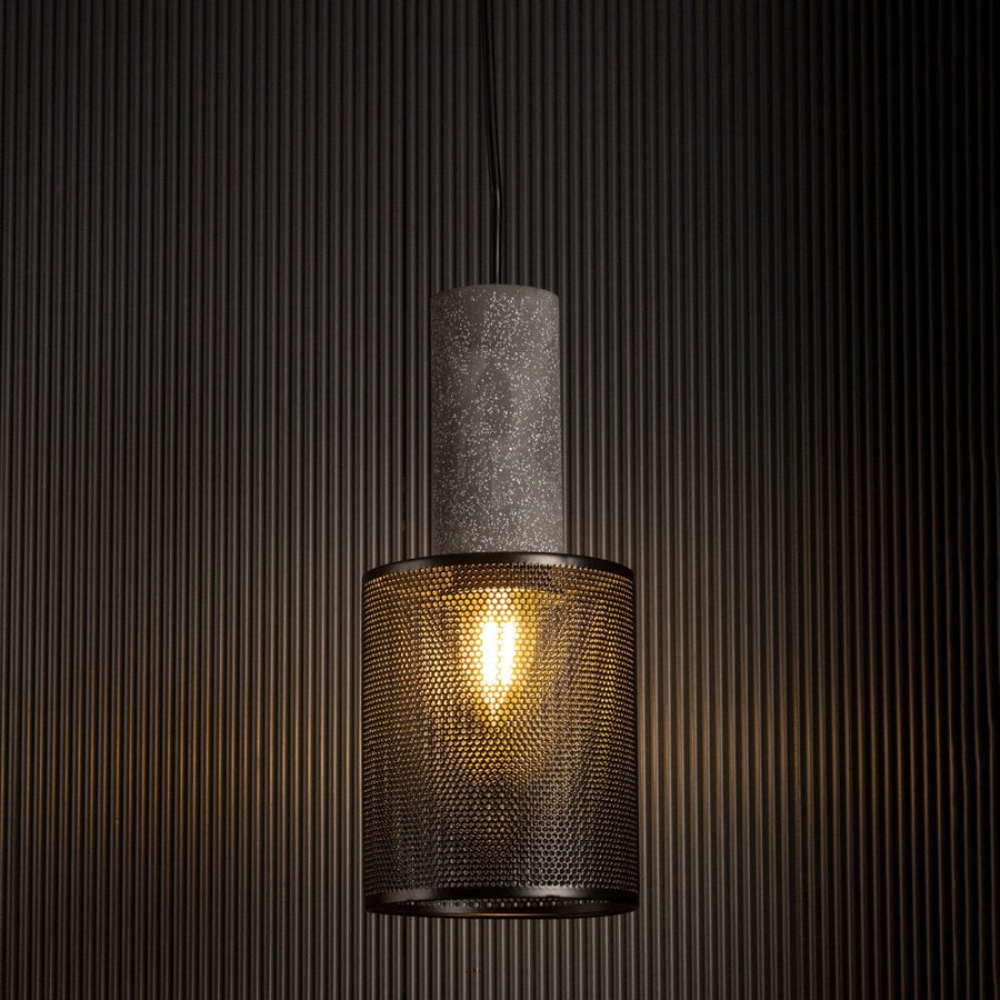 Arlo Mesh pendant light glowing against a dark background highlighting industrial texture and warm filament light.