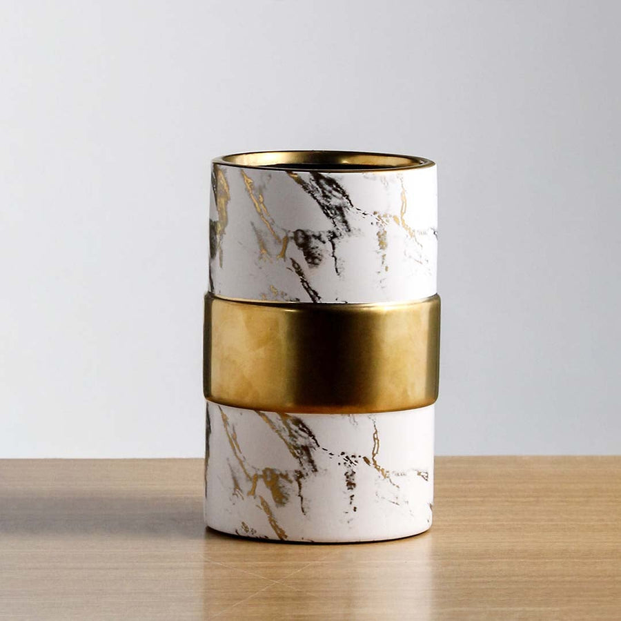 Closeup of decorative marble finish candle holder with gold metal band smooth surface and luxury tabletop decor styling.
