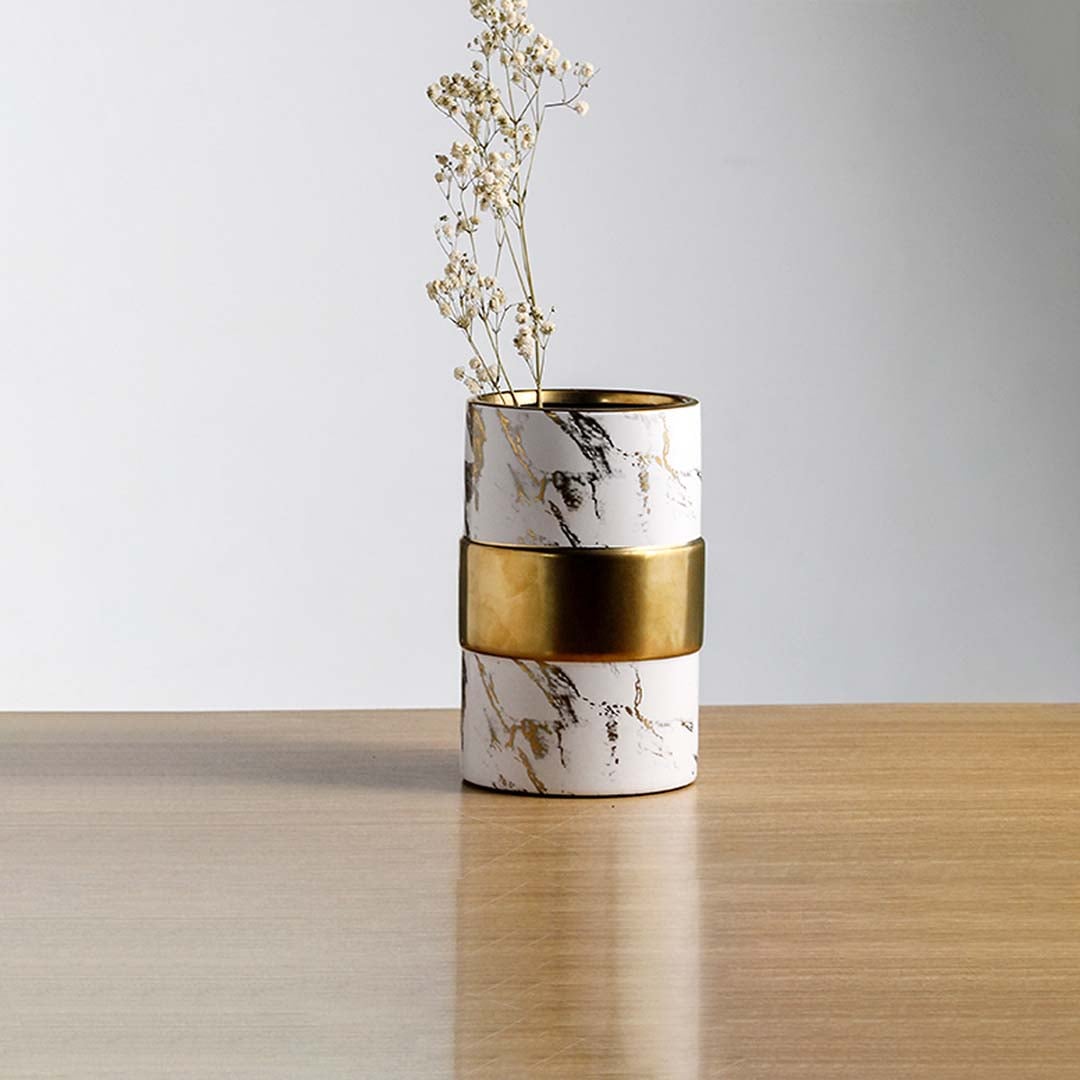 White marble finish metal candle holder with gold accent placed on wooden table adding modern luxury touch to home Decor.