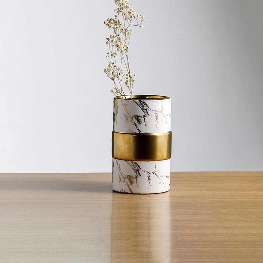 White marble finish metal candle holder with gold accent placed on wooden table adding modern luxury touch to home Decor.
