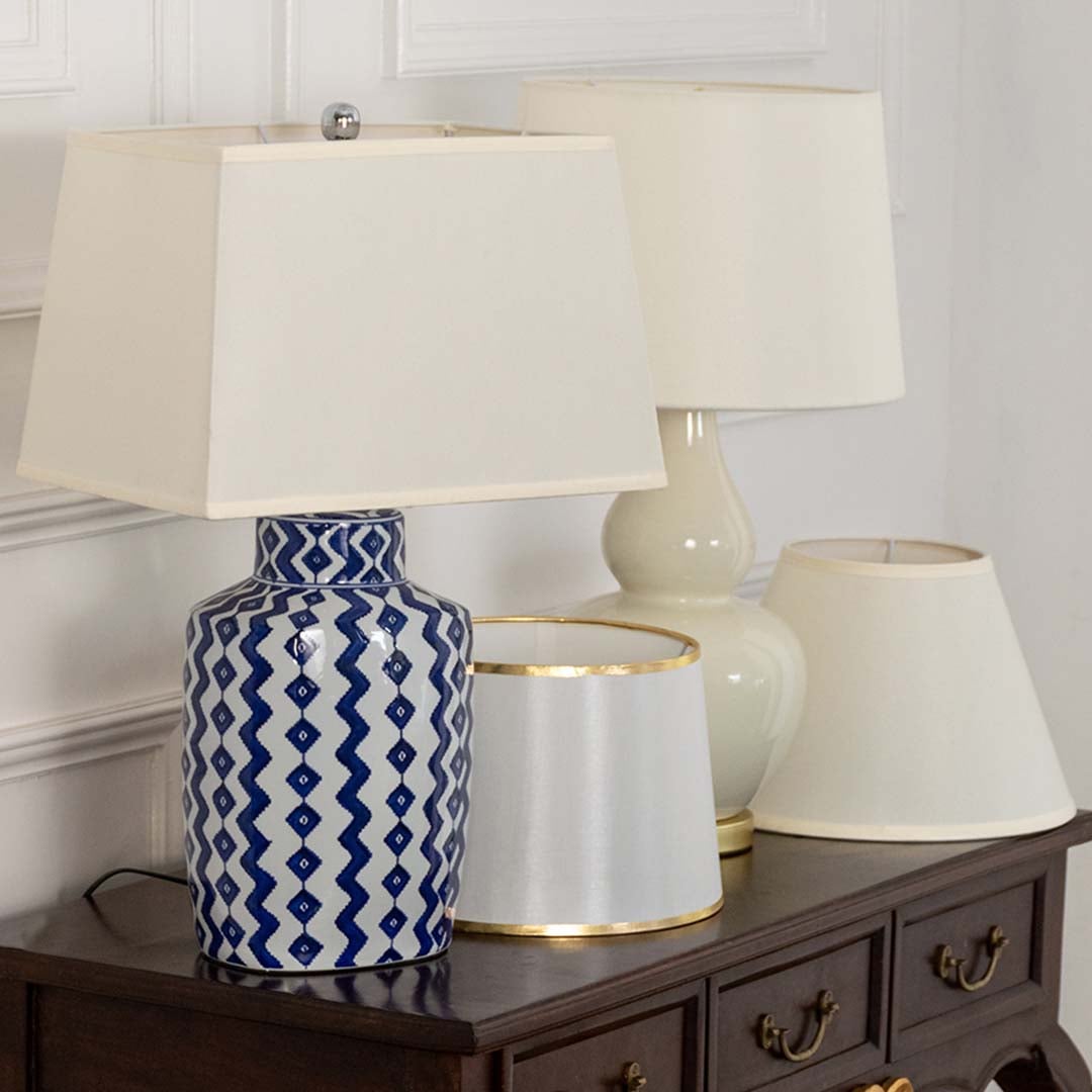 Blue patterned ceramic table lamp with white shade on wooden sideboard with light off for classic decorative home décor.
