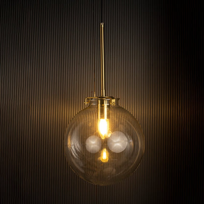 Glass globe pendant light glowing warmly against a dark background showing elegant glass craftsmanship and gold detailing.