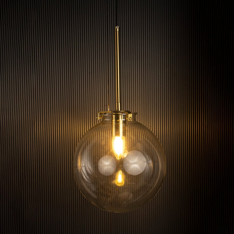 Glass globe pendant light glowing warmly against a dark background showing elegant glass craftsmanship and gold detailing.