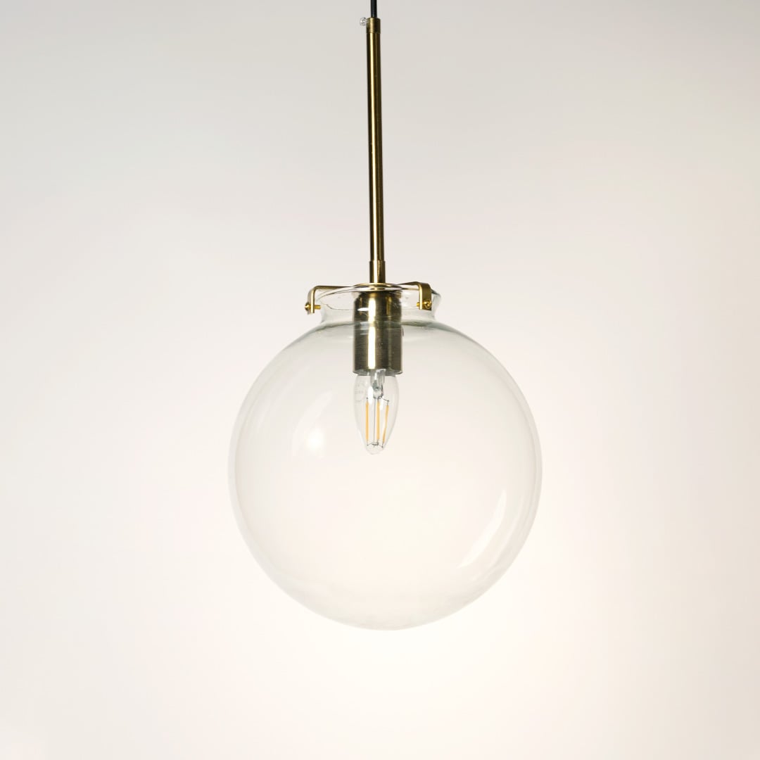Glass globe pendant light on white background with light off showing clear round glass design and brass fitting.