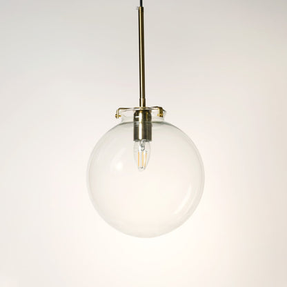 Glass globe pendant light on white background with light off showing clear round glass design and brass fitting.