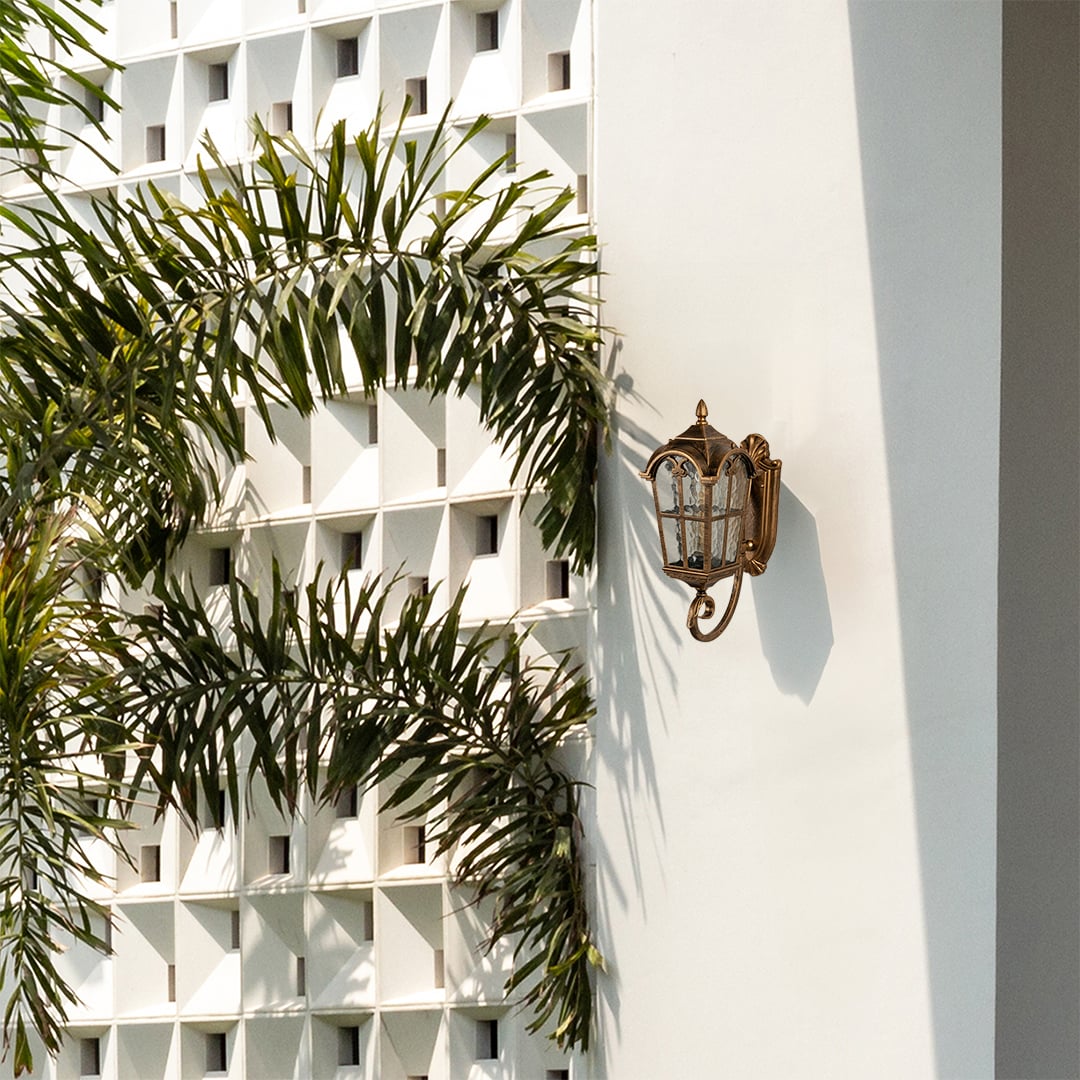 Gold metal outdoor wall lantern with warm light on enhancing the exterior wall and garden view for premium outdoor lighting decor.