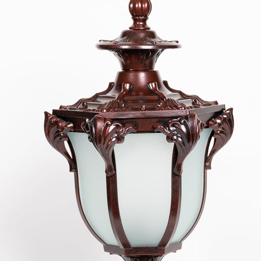 Detailed closeup of outdoor brown metal pillar lamp with frosted glass shade and intricate vintage decorative design.
