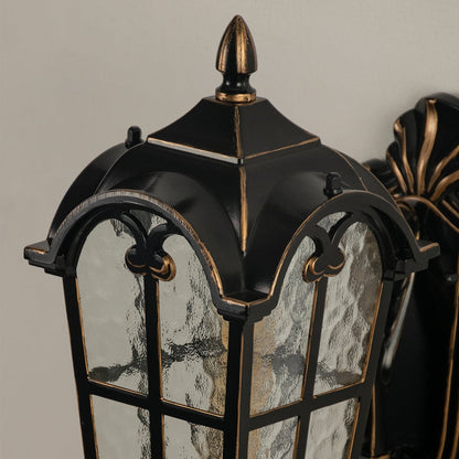 Black metal outdoor wall light closeup image with textured water glass shade and vintage gold edge trim for decor.