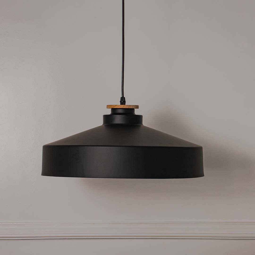 Black metal pendant light with wide drum shade crafted for modern kitchens and dining spaces.