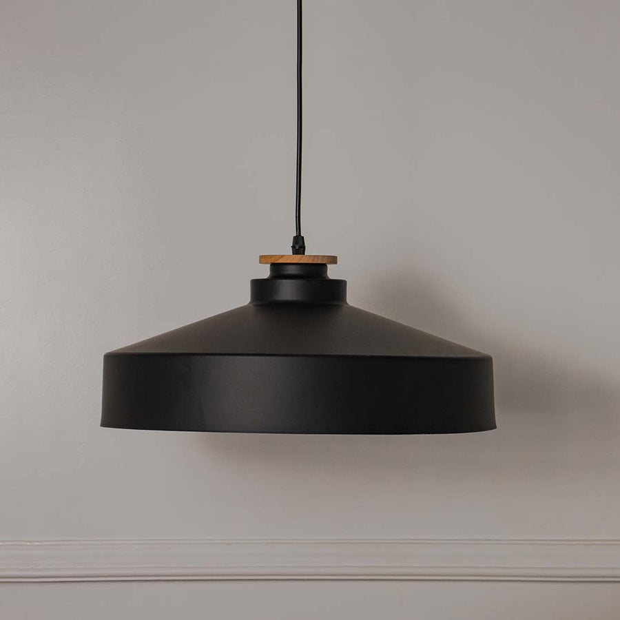 Black metal pendant light with wide drum shade crafted for modern kitchens and dining spaces.