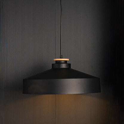 Matte black dome pendant lamp with industrial metal shade and wooden accent glowing warmly on black background decor.
