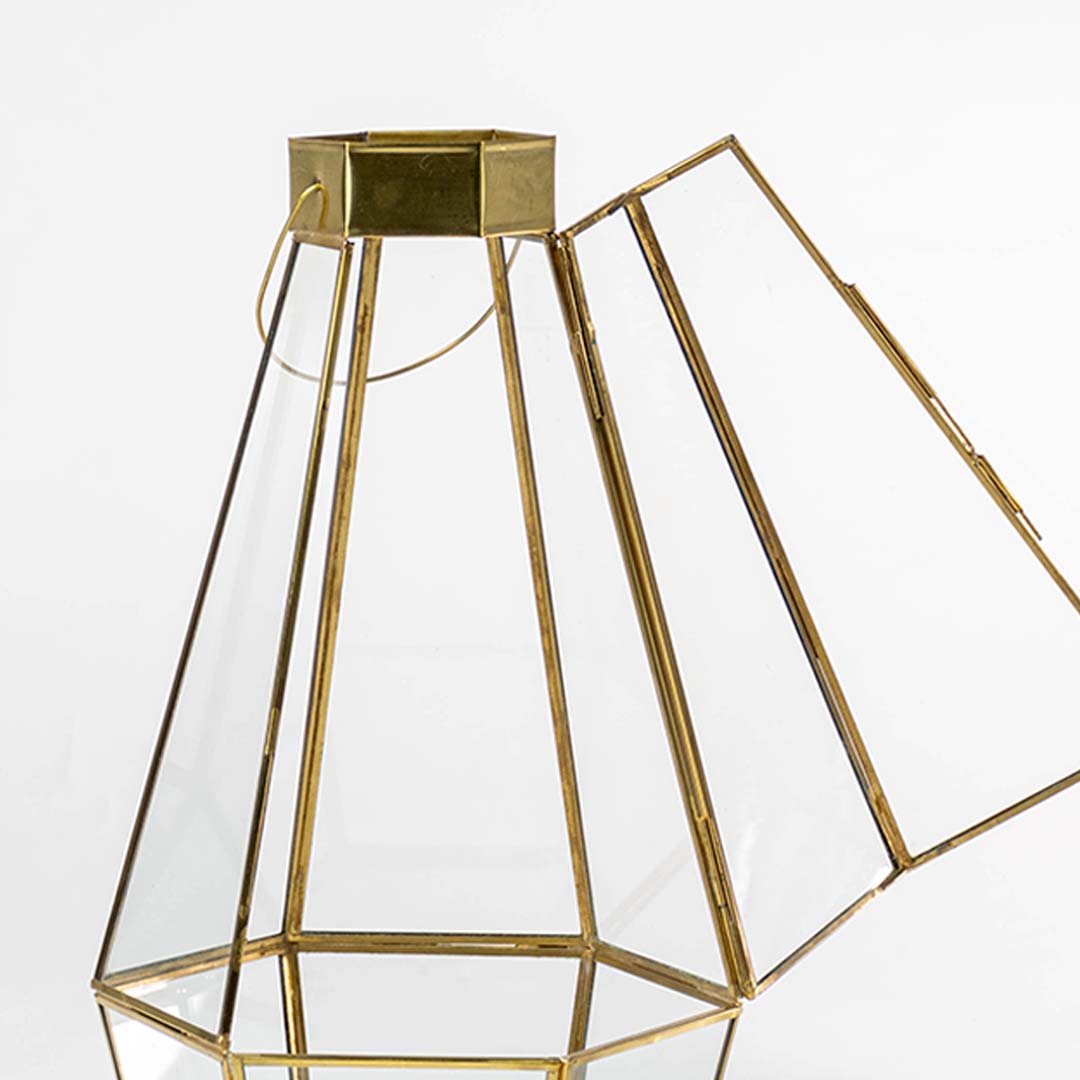 Closeup of gold geometric lantern showing clear glass panels and refined metal frame detailing creating a premium modern decorative accent.
