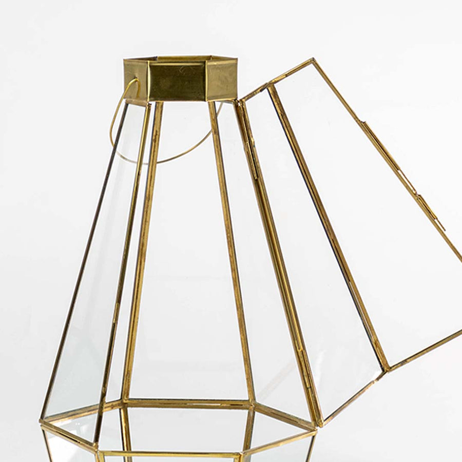 Closeup of gold geometric lantern showing clear glass panels and refined metal frame detailing creating a premium modern decorative accent.