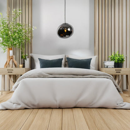 A sculpted smoked glass pendant light illuminated above a cozy bedroom adding warm ambient lighting ideal for bedsides living rooms and lounge spaces.