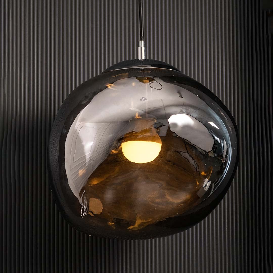 A modern smoked glass pendant light glowing warmly against a dark textured wall creating a rich ambient lighting effect for luxury interior styling.