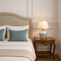 Table lamp with a soft blue and white ceramic base and gold metal accents with a white shade bringing a modern yet timeless touch to home decor.