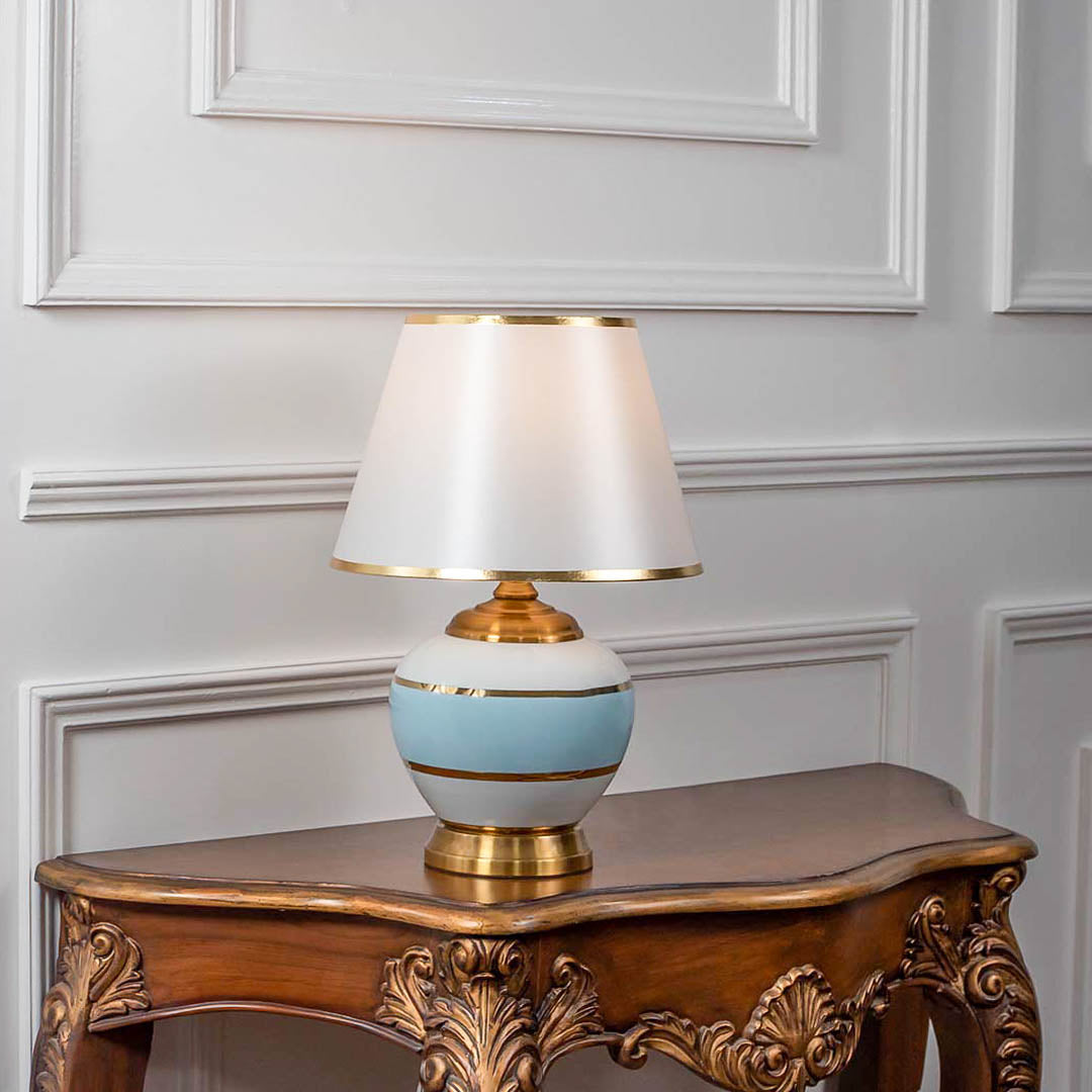 White ceramic table lamp with fabric shade displayed on a carved wooden console table creating elegant traditional lighting.