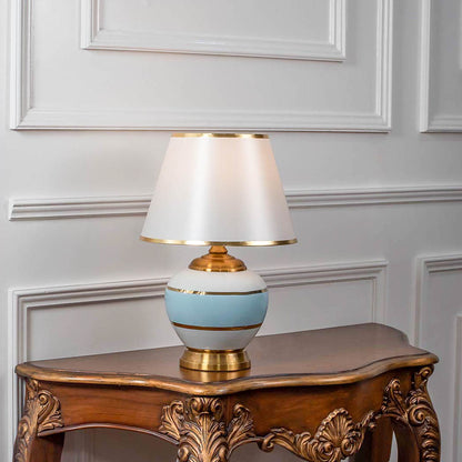 White ceramic table lamp with fabric shade displayed on a carved wooden console table creating elegant traditional lighting.