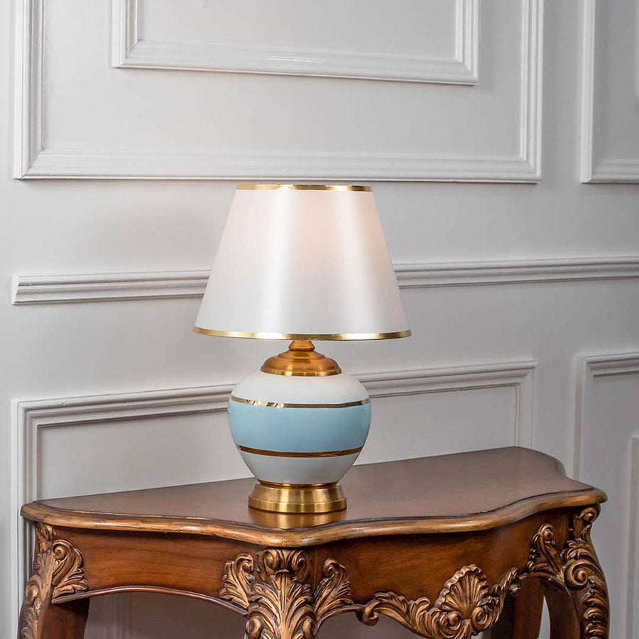 White ceramic table lamp with fabric shade displayed on a carved wooden console table creating elegant traditional lighting.